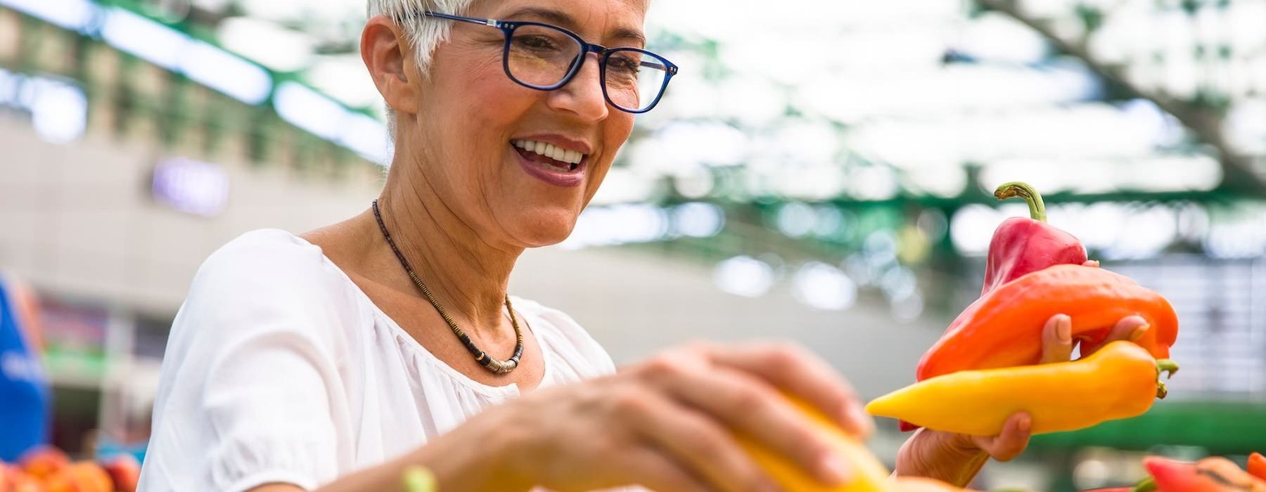 a woman smiling and holding a bunch of vegetables